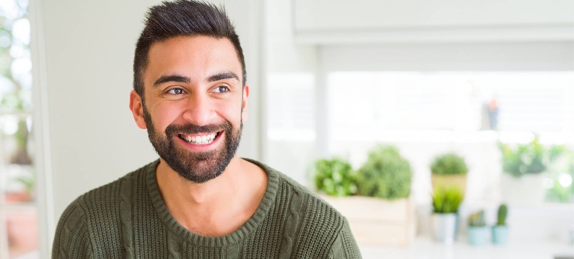 Man in cabled green sweater in kitchen smiling