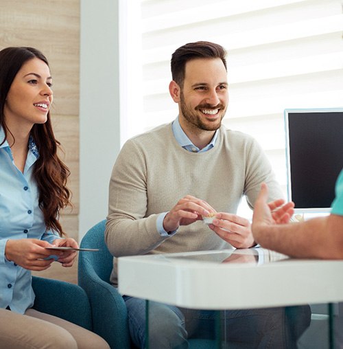 Dentist and couple talking in dental office